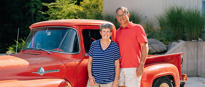 two people stand beside a red truck