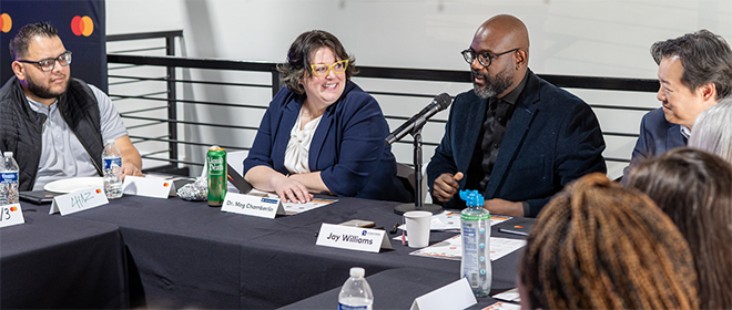 Jay Williams speaks at a round table discussion, with the other business leaders smiling and listening around him.